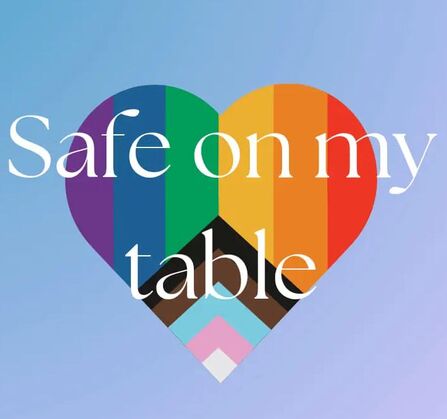 picture of Pride flag in a heart shape with the words 'safe on my table' over it in white